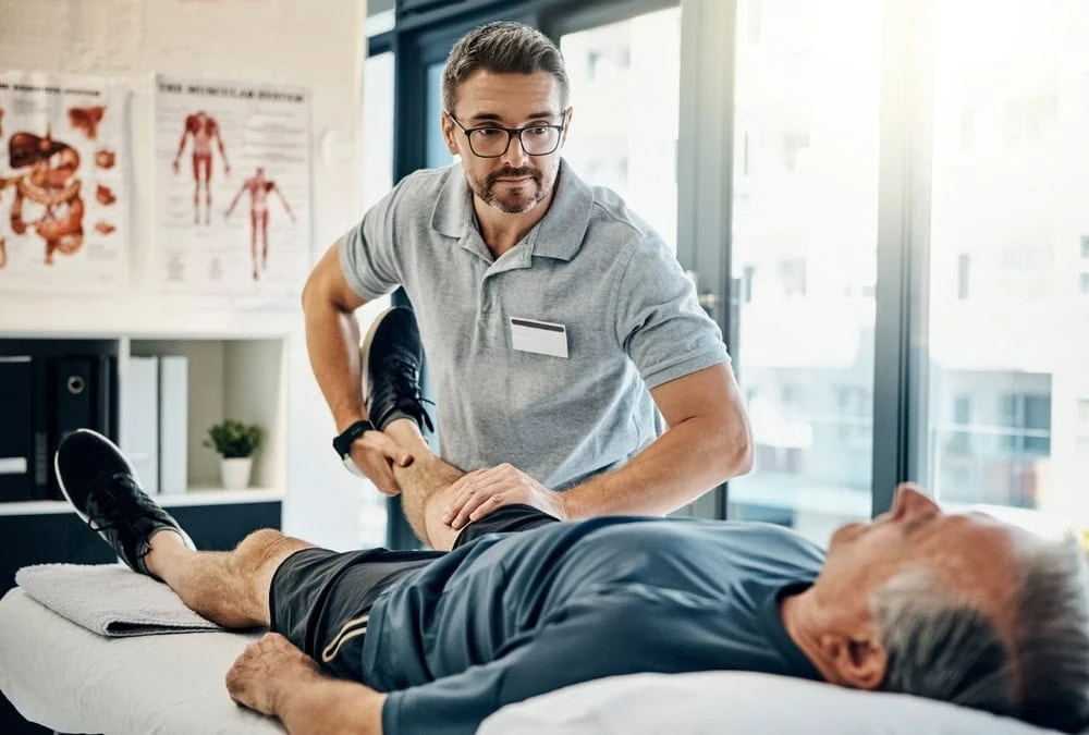 A physical therapist in NYC guiding a patient through rehabilitation exercises in a clinical setting, focused on recovery, pain relief, and restored mobility.