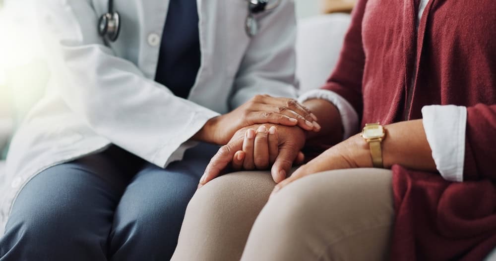 A compassionate doctor in NYC holding a patient’s hand before a kyphoplasty procedure, symbolizing expert care, support, and advanced spine treatment for vertebral compression fractures.